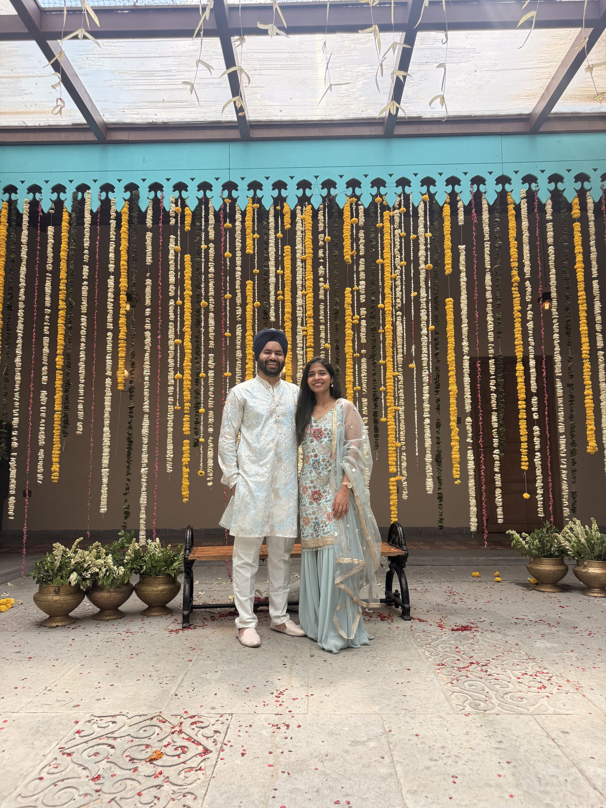 Ashrita and Gursimran beneath marigold garlands